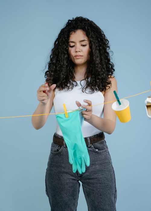 Free A woman hanging recyclable items such as gloves and cups on a line, promoting zero waste. Stock Photo