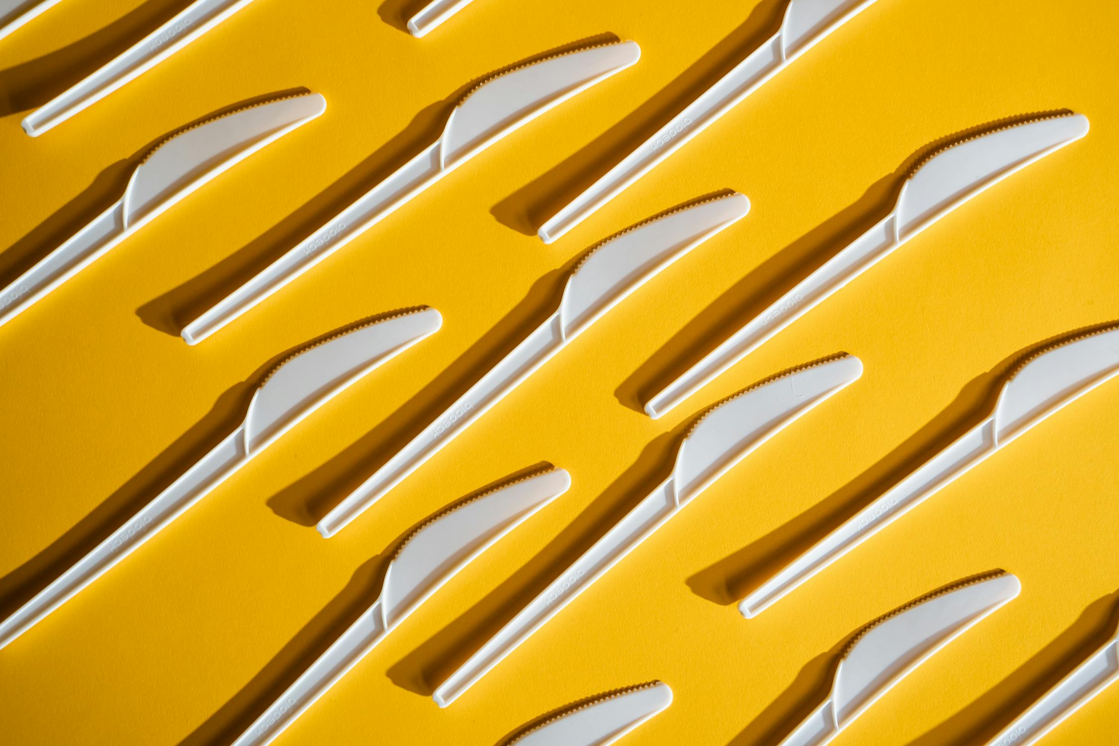Arranged Plastic Knives on Yellow Surface