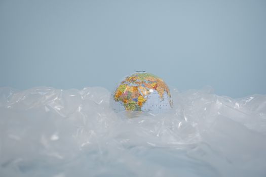 A globe surrounded by plastic, highlighting global environmental pollution issues.