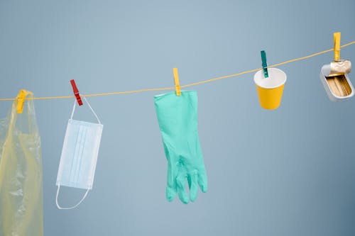 Teal Rubber Gloves Hanging Beside Facemask and Yellow Cup