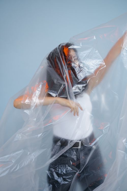 Free Creative portrait of a woman posing behind clear plastic sheet, showcasing modern conceptual art. Stock Photo