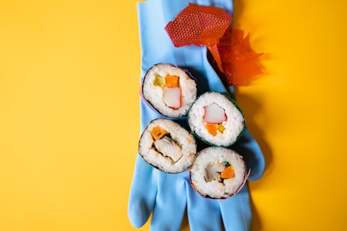 Sushi Wrapped in Plastic Foil Served on Rubber Glove