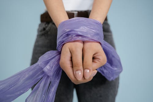 Person in Gray Denim Jeans with Hands Tied with Purple Plastic