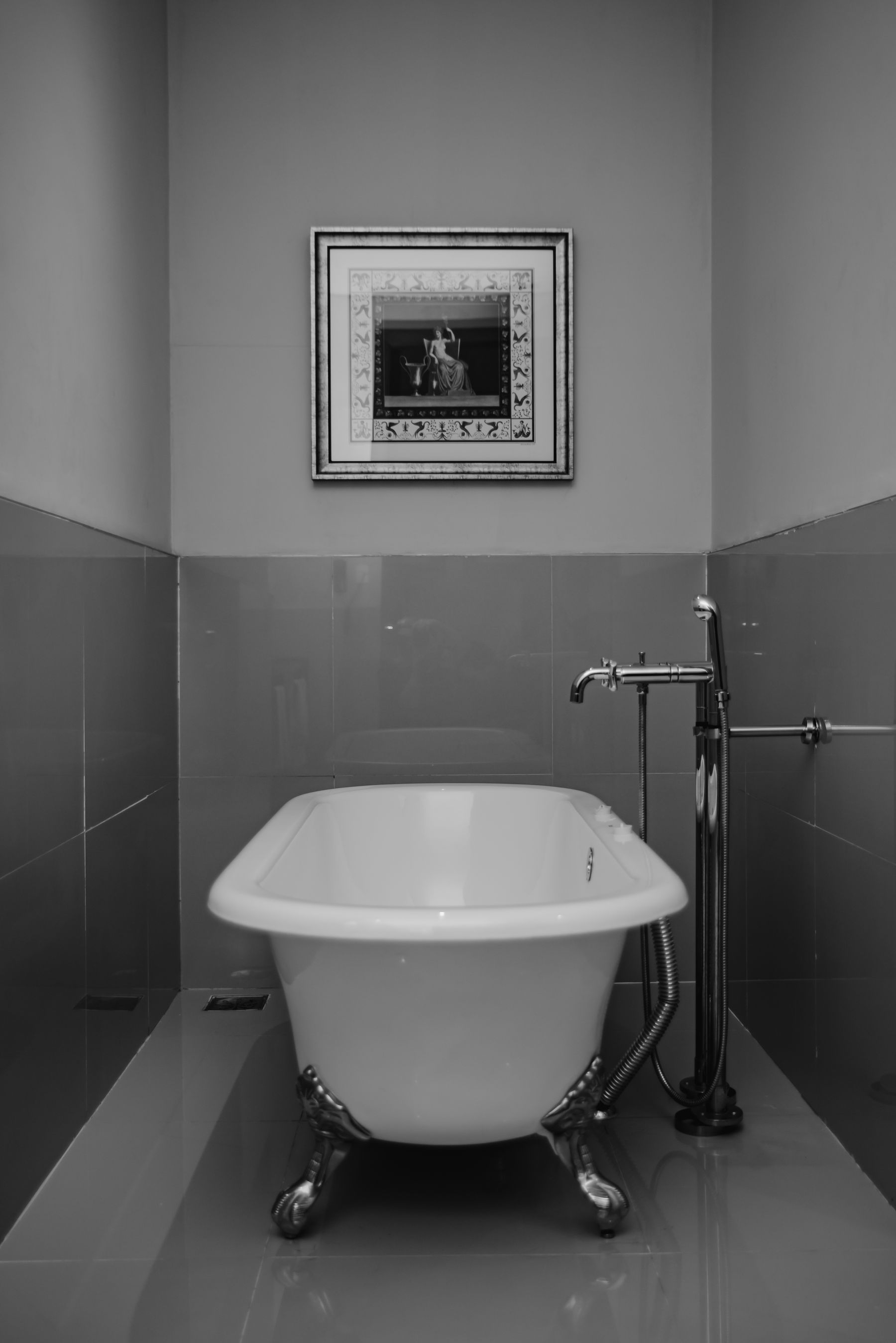 Black-and-white bathroom with classic clawfoot tub and framed art