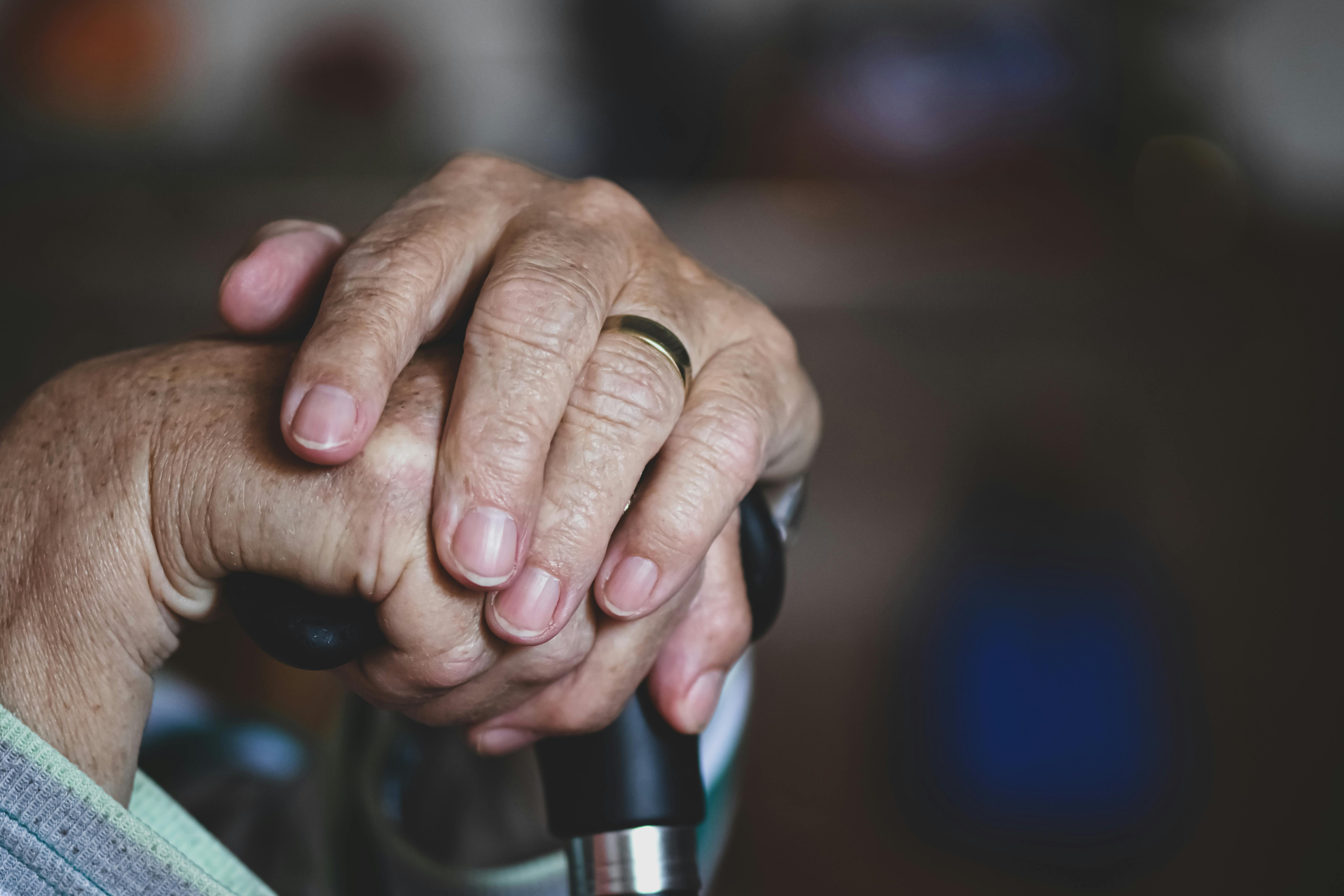 hands of an elderly person resting on a cane