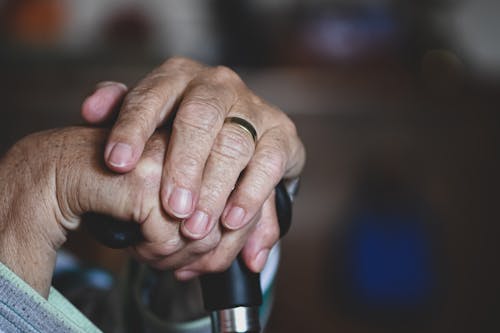 Hands of an Elderly Person Resting on a Cane