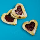 在充满活力的蓝色背景上，摆放着果酱填充的心形饼干，美味诱人