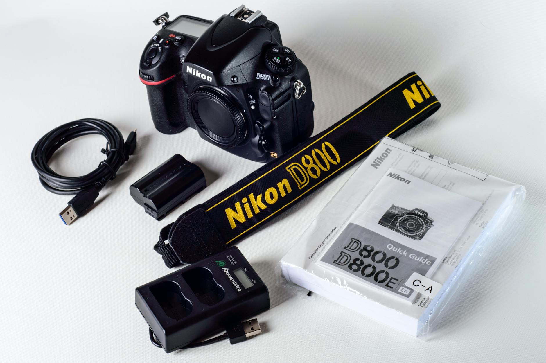 Nikon D800 camera setup with strap, USB cable, charger, and manual on a white background.