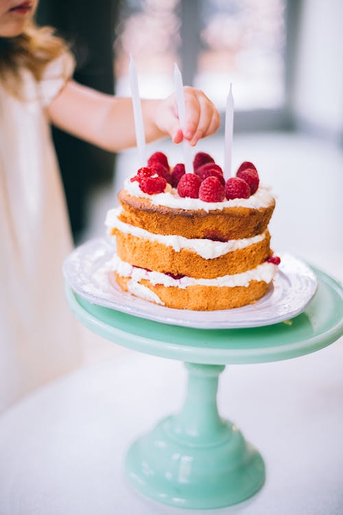 Free Girl Putting a Candle on 3-layered Cake Stock Photo
