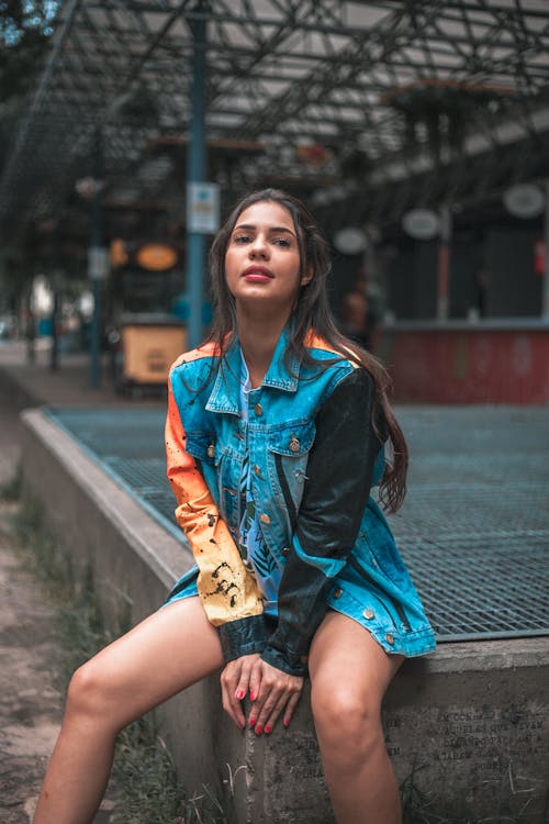 Free Photo of a Woman in a Denim Jacket Sitting on a Concrete Surface Stock Photo