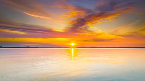 Free A breathtaking sunset with vibrant colors reflecting on calm ocean waters, capturing nature's beauty. Stock Photo