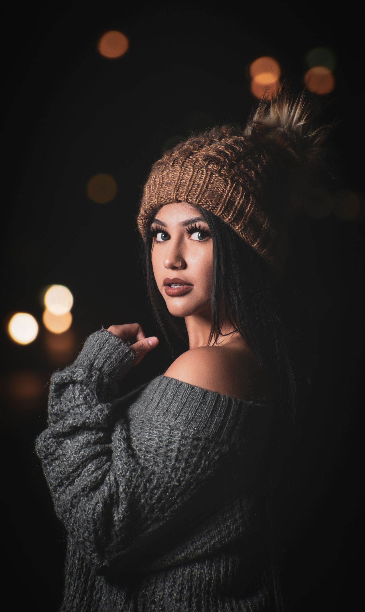 Woman in a chunky knit sweater and knit beanie at night