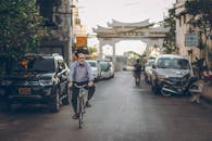 一名男子在安静的街道上骑自行车，背景是停放的汽车和文化建筑