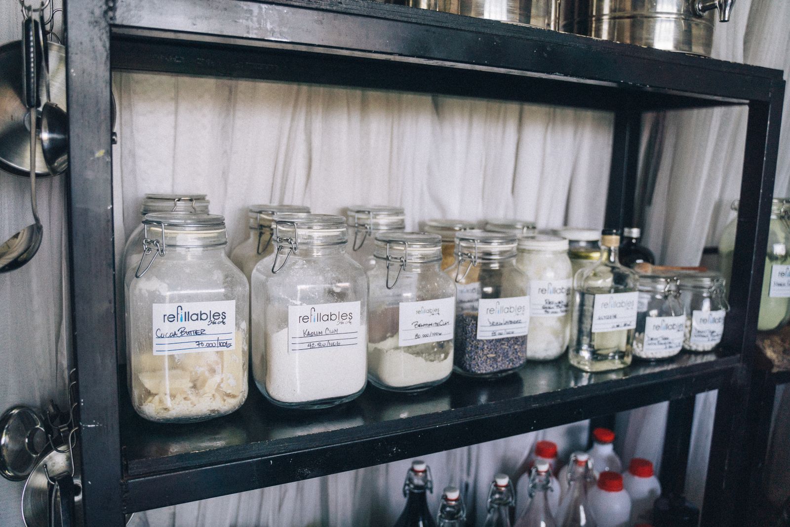 Glass jars on a black shelf in a kitchen pantry.