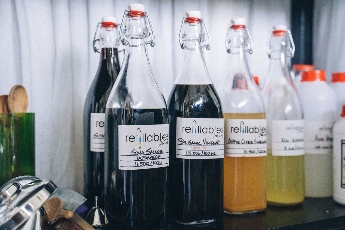 Refillable glass bottles arranged on a clean wooden shelf