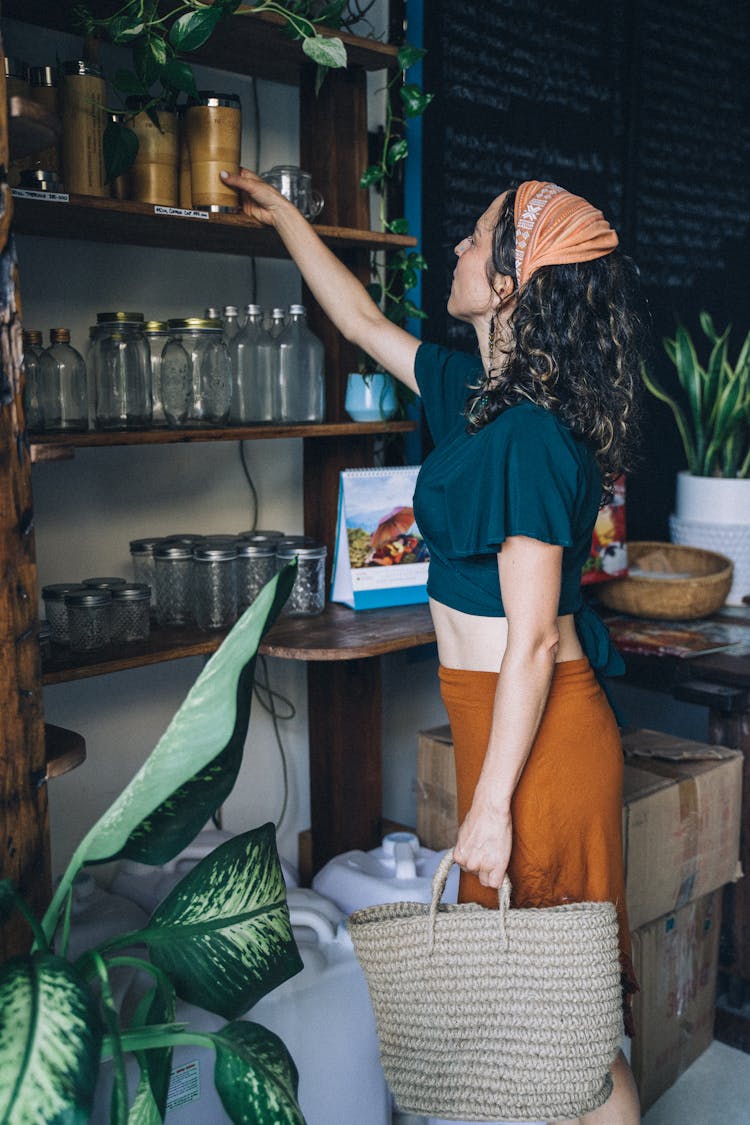 Woman Picking Up A Cup On Brown Wooden Shelf