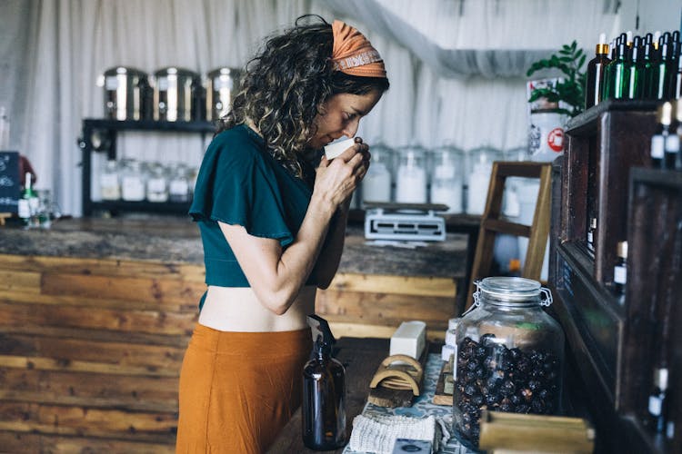 Woman In Blue Shirt And Brown Skirt Smelling A Soap