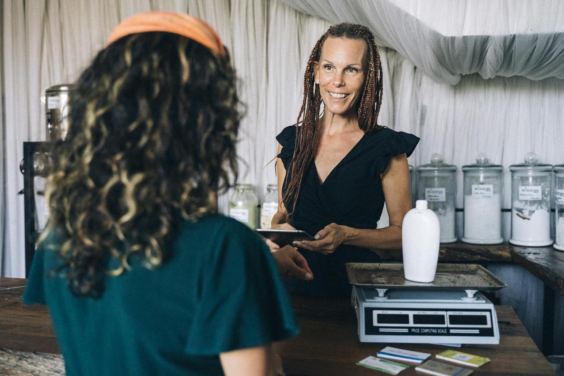 A woman assists a customer with a reusable container at a zero waste store, promoting sustainable shopping.