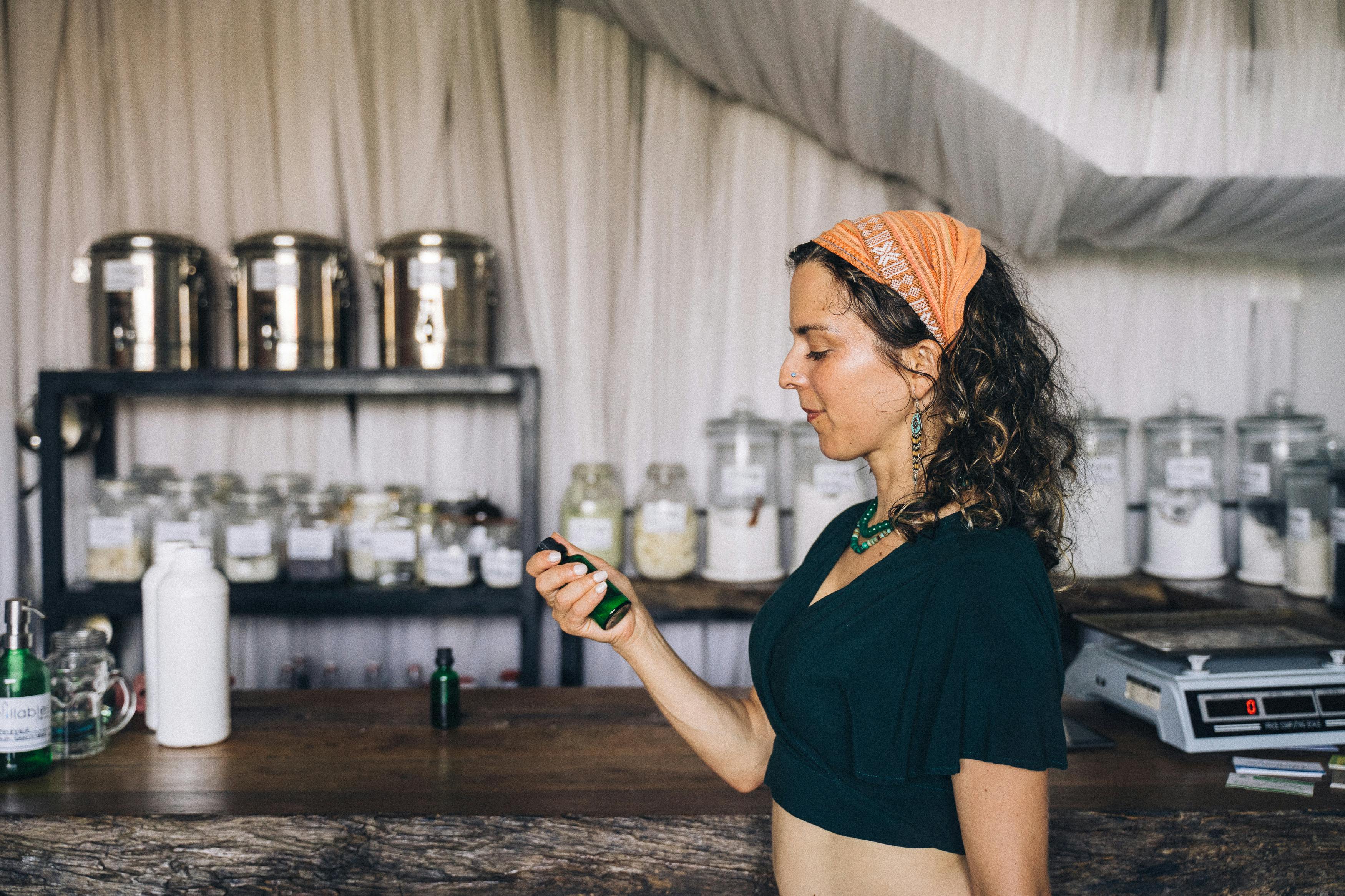 Woman holding a green bottle inside a zero waste store, emphasizing sustainability.