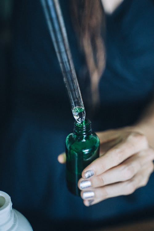 A Person Holding Green Glass Bottle