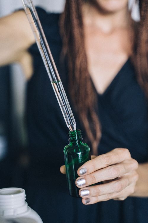 Free Close-up of hands refilling a reusable glass bottle using a dropper, emphasizing sustainability. Stock Photo
