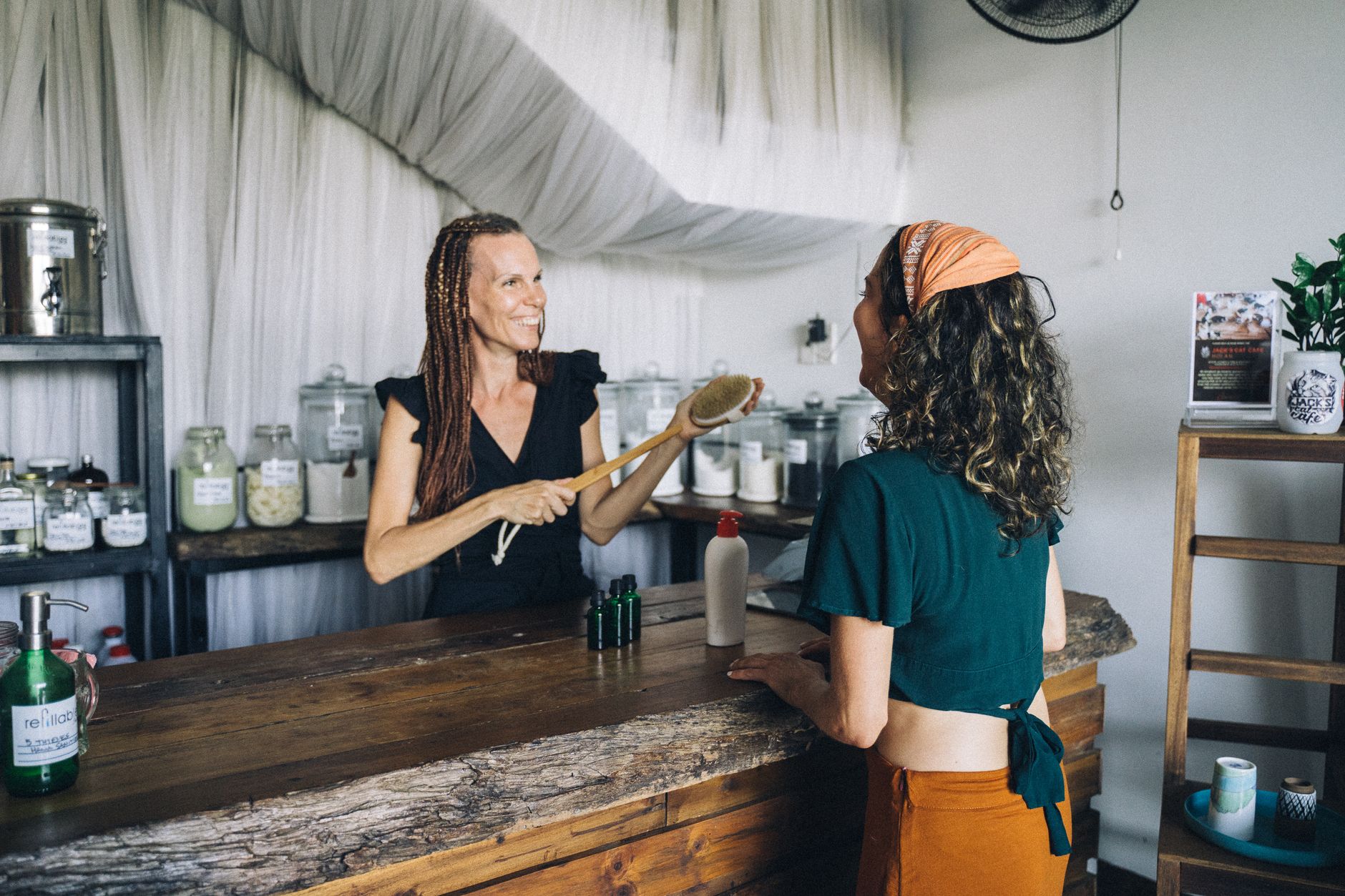 A customer buying natural skincare products from a cheerful shop owner.