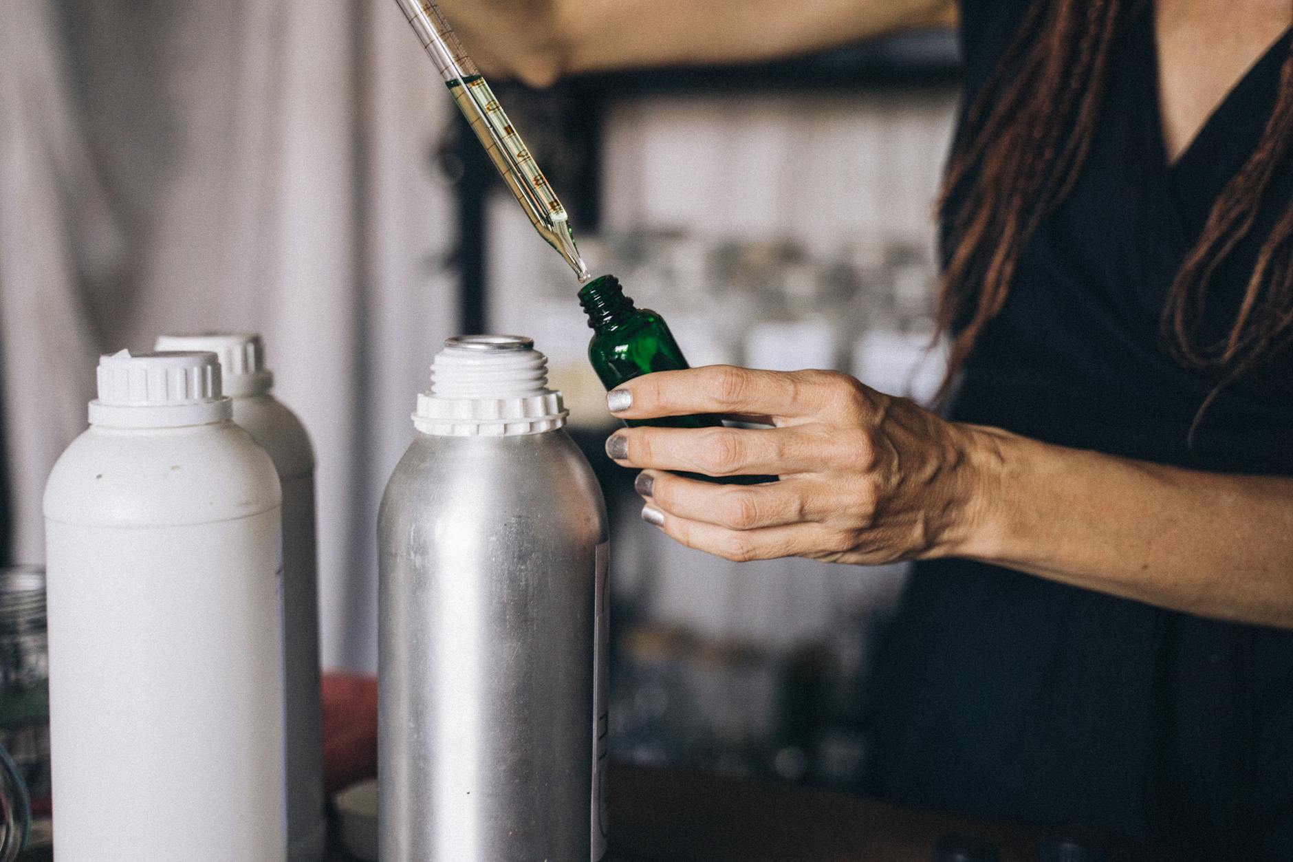 Woman Putting Oil Into a Green Glass Bottle