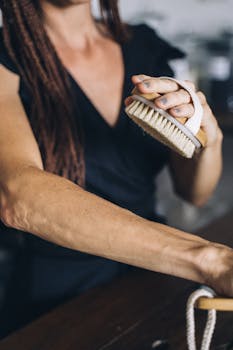 Close-up of a woman using a body brush for skin exfoliation, promoting wellness.