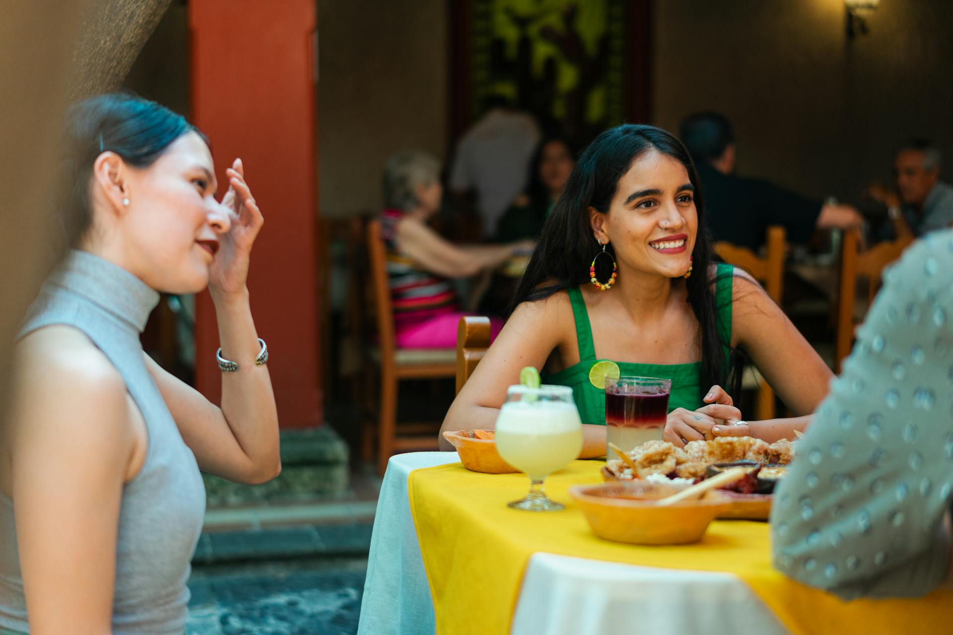 Group of friends enjoying food and drinks at a Mexican restaurant, capturing a lively and festive atmosphere outdoors.