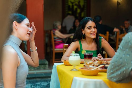 Free Group of friends enjoying food and drinks at a Mexican restaurant, capturing a lively and festive atmosphere outdoors. Stock Photo