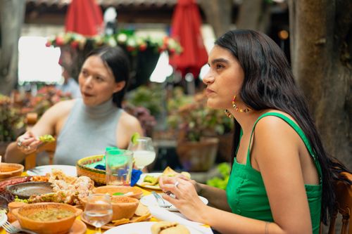 Free Women enjoying Mexican cuisine outdoors. A lively scene of culture, tradition, and delicious food. Stock Photo