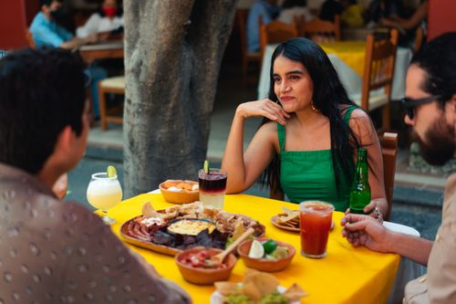 Free Friends enjoy Mexican cuisine at an outdoor restaurant, sharing laughter and traditional dishes. Stock Photo