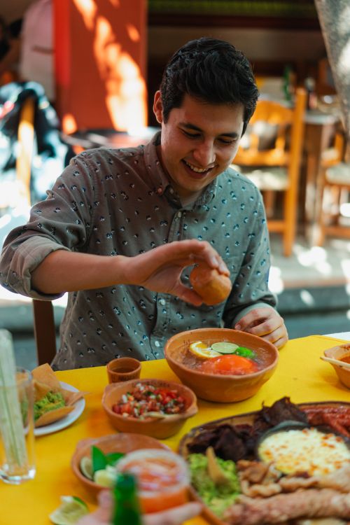 Free A smiling young man enjoys a colorful Mexican meal at a vibrant restaurant. Stock Photo