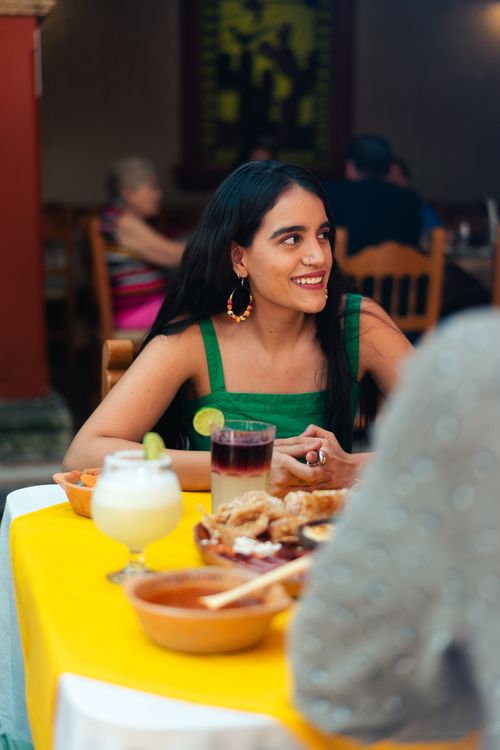 Free Young woman at a Mexican restaurant smiling, enjoying traditional food and drinks. Stock Photo