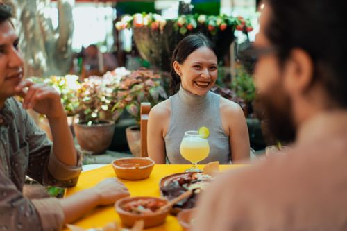 Free Smiling group of friends at a Mexican restaurant enjoying food and drinks outdoors. Stock Photo