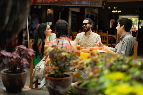 Free Friends enjoying a meal and conversation in a lively Mexican restaurant setting. Stock Photo