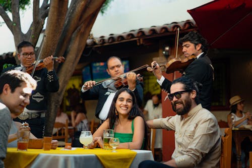 Free Group of Friends Eating while Listening to Mariachi Band Stock Photo