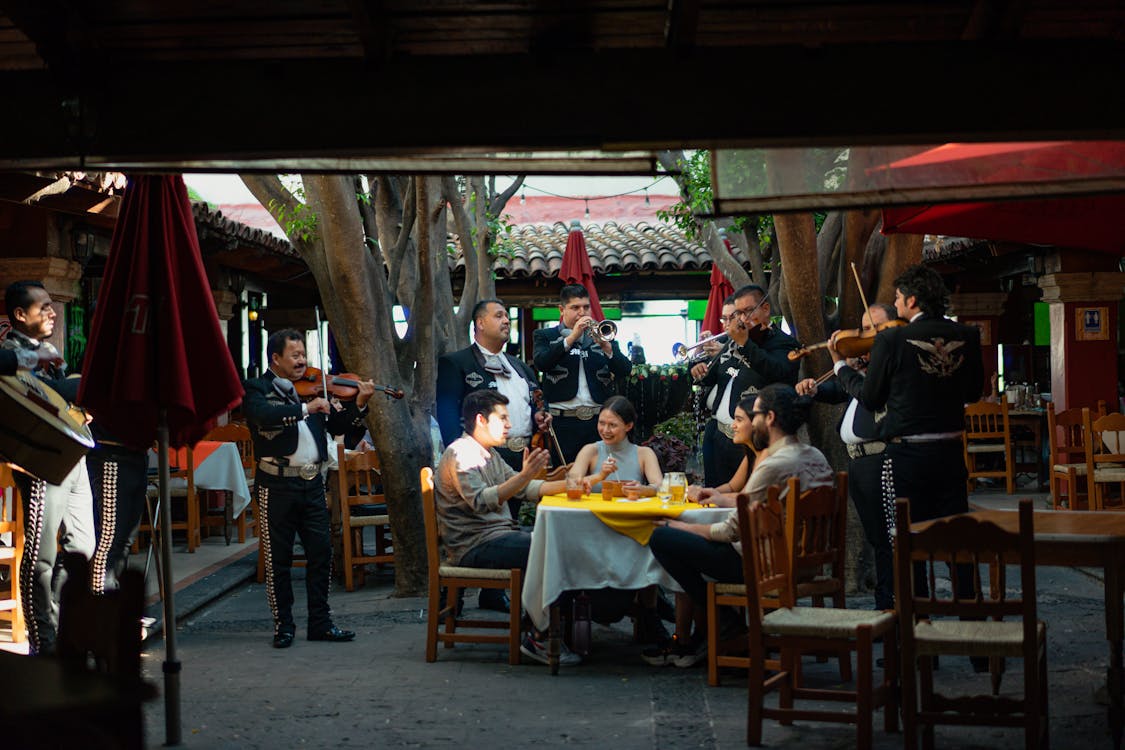 Free Group of Friends Eating while Listening to Mariachi Band Stock Photo