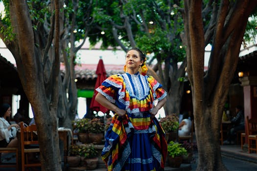 A smiling woman in traditional Mexican dress celebrates culture in a vibrant outdoor setting.