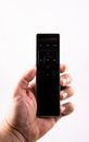 Crop unrecognizable person showing remote control with buttons on white background in studio