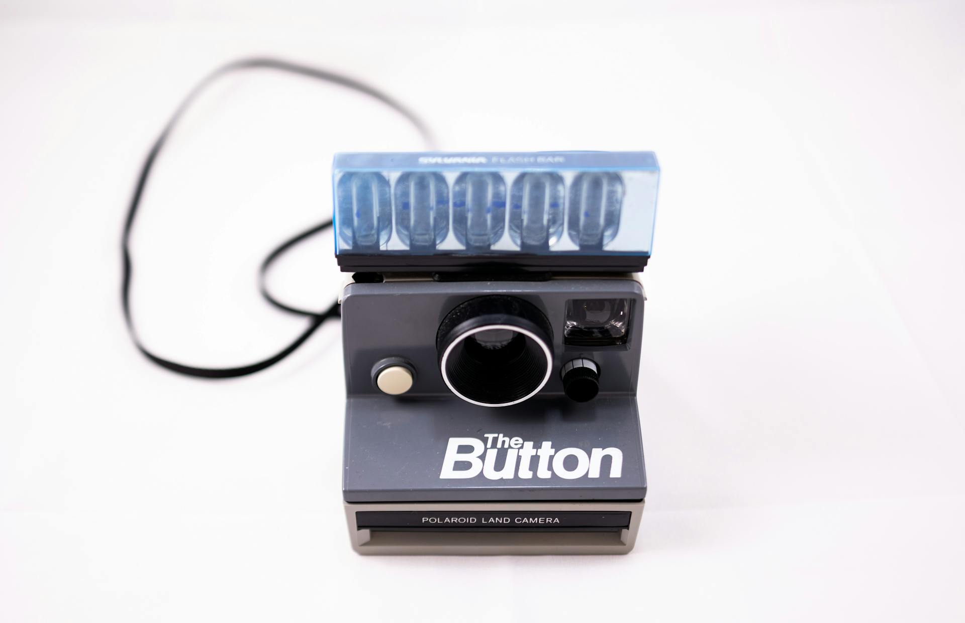 From above of film instant photo camera placed in studio against white background