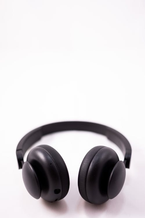 Free From above of modern shiny black wireless headphones placed on white background in light studio Stock Photo