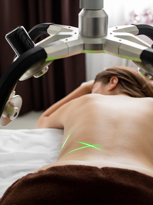Unrecognizable topless woman under laser weight loss machine