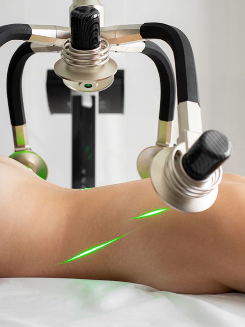 Free Crop anonymous topless female patient lying under green lasers of modern fat loss machine with heads in light medical clinic Stock Photo