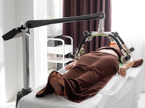 Free Unrecognizable female under laser weight loss machine on medical table Stock Photo