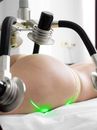 Crop unrecognizable female doing non invasive laser body shaping treatment in modern clinic