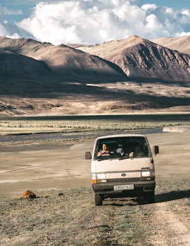 A van travels off-road through a breathtaking mountainous landscape, perfect for adventurous road trips.