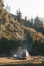 Unrecognizable travelers near tent in forest