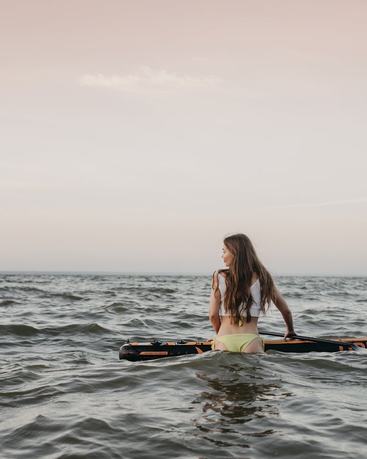 Woman Floating On Paddleboard In Sea