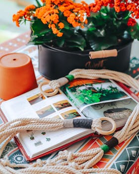 Vibrant scene with open gardening book, flowers, rope, and terra cotta pot, perfect for horticulture themes.